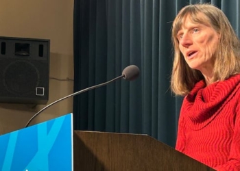 A woman speaks behind a podium.