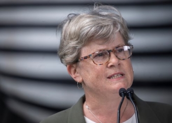 A white woman with short hair speaks into a mic.