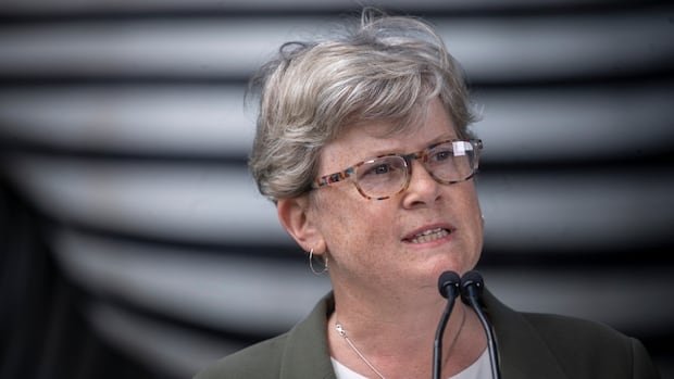 A white woman with short hair speaks into a mic.