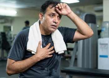 An Indian man after a workout is worried after his heart that suddenly starts racing, with his hand on his heart