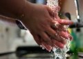 Associated Press reporter Zen Soo washes her hands at a sink while wearing a quarantine wristband during her two-week quarantine at home in Hong Kong on April 17, 2020.