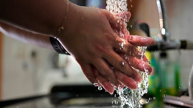 Associated Press reporter Zen Soo washes her hands at a sink while wearing a quarantine wristband during her two-week quarantine at home in Hong Kong on April 17, 2020.