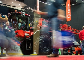People walk a by a big combine.