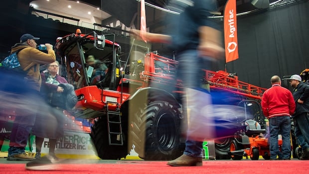 People walk a by a big combine.