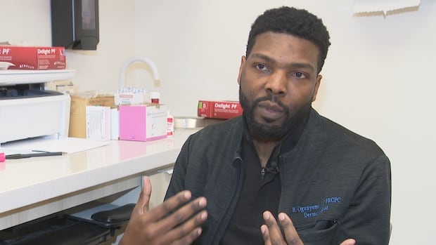 A man in his thirties sits in a medical office speaking with a reporter