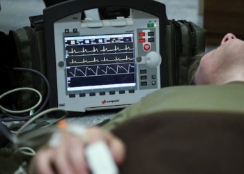 An electrocardiogram instrument (ECG) stands next to a simulated casualty during a first aid drill.
