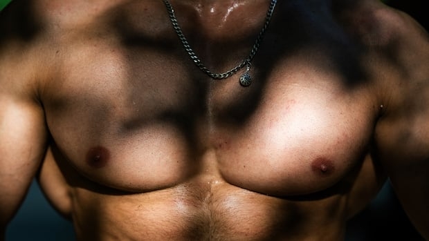 A man poses showing his muscled chest at Bercy street workout outdoor gym, in Paris, on August 10, 2025.
