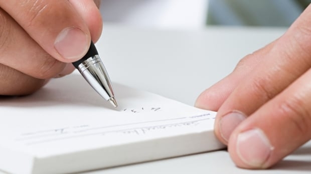 Close up of hand holding a pen writing on a prescription pad.