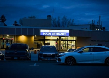 It's night time and the Mission Memorial Hospital main entrance sign is lit with several cars in front of the hospital.