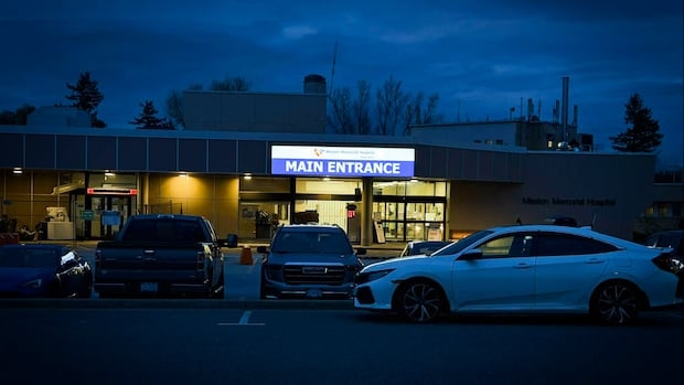 It's night time and the Mission Memorial Hospital main entrance sign is lit with several cars in front of the hospital.