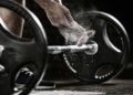Athlete prepares to lift free weights with chalky hands.