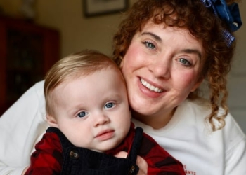 A woman with curly hair holds her infant son.