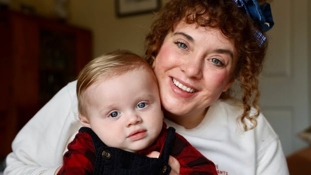 A woman with curly hair holds her infant son.