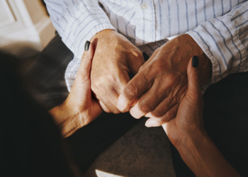 A woman holds the hands of a senior man.
