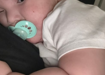 A baby with a soother looking sombre