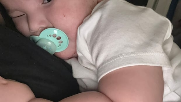 A baby with a soother looking sombre